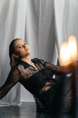 Mysterious young woman in black lace gazes intensely through candlelight, evoking elegance and...