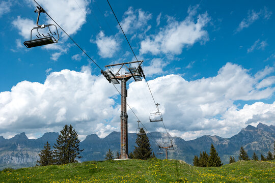 Empty and unoccupied ski lift during summer, Chatzenberg, Swiss Alps. Switzerland, Canton St. Gallen. Sky with clouds. Hiking, traveling, tourism, destination, recreation, leisure activity.