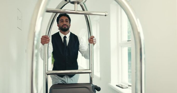 Man, hotel and service with luggage trolley, push and bag delivery for client at job in hallway at luxury lodge. Person, bellboy and porter with guest baggage, concierge and accommodation at resort