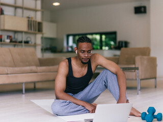 Training At Home. Sporty man doing the training while watching an online tutorial on a laptop,...