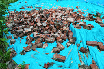 Scattered broken bricks on blue protective film at a construction site.