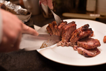 A close-up of chef slicing a flavorful, grilled steak on a white plate, showcasing the meat's juicy...