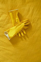 Bright yellow cleaning gloves placed neatly on a vibrant yellow surface in a cozy indoor setting...