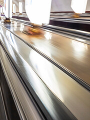 Moving along a metal escalator in a modern indoor space with bright lighting and sleek design...