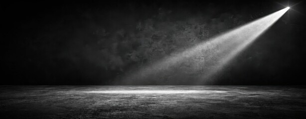 A spotlight shining on a dark textured floor in a black and white studio background with copy space