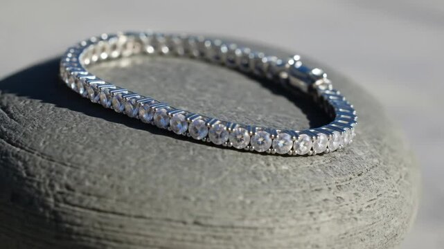 Elegant diamond bracelet jewelry on grey stone surface in natural light, sparkling diamonds.