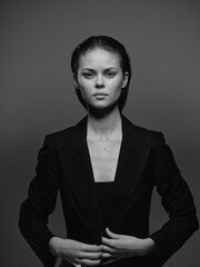 Black and white portrait of a serious woman wearing a stylish blazer with slicked-back hair,...