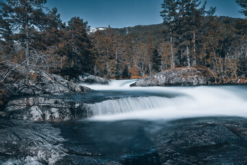 long exposure waterfall in norway with trees in background