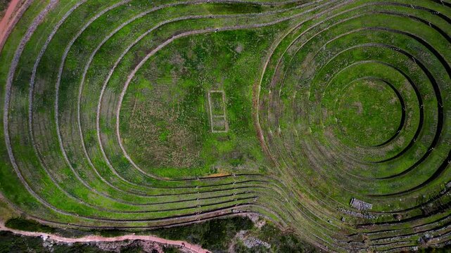 Circular Moray terraces in Peru, showcasing Inca agricultural engineering in vibrant green landscape - top-down aerial trucking
