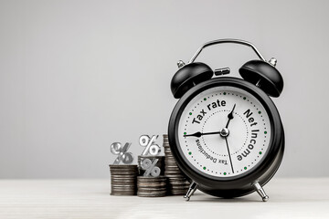 Black alarm clock with the words Tax Rate, Tax Deductions and Income between the hands clock....
