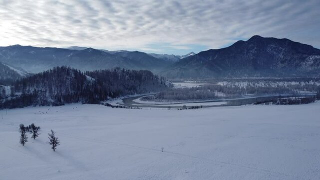 Drone footage of snowy mountains, valleys, and forests in Ust-Koksa, Altai Republic, Russia, under clear skies, showing the remote region&rsquo;s beauty during winter.
