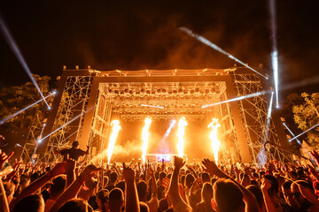 Crowd enjoying live music concert with fire show and light effects