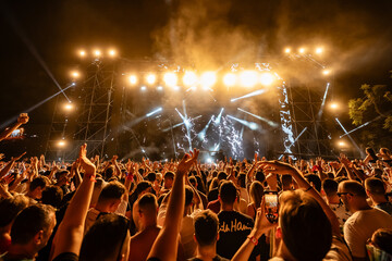 Crowd enjoying live music concert with stage lights and smoke at night