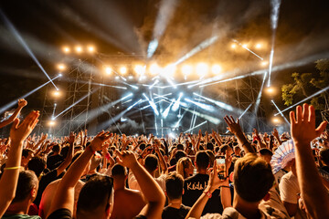 Crowd enjoying live music concert with stage lights and smoke at night