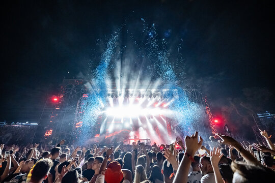 Crowd enjoying live music concert with stage lights and confetti at night