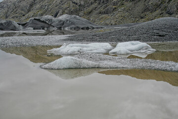Glacier with black lava ice melting in lake