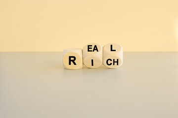 Real rich symbol. Turned wooden cubes with words 'Real rich'. Beautiful grey table, beige...