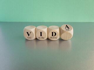 Cubes form the acronym ViDA VAT in the digital age. Beautiful blue background, gray table. Business...