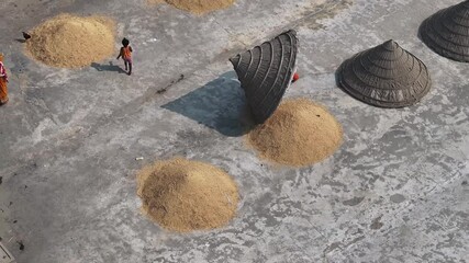 Dhaka, Bangladesh - 01 March 2025: Aerial view of woman drying grain on rooftop, Bangladesh.