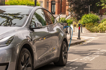 Electric car being charged on upmarket British residential street