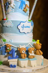 A three-tier blue and white birthday cake decorated with fondant, figurines in the shape of bears and a bunny with the male name Philip written in Cyrillic.