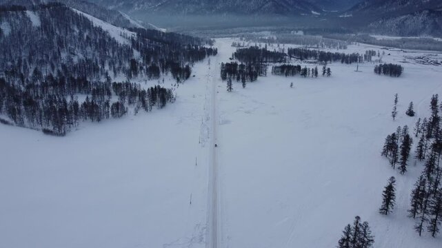 Drone footage of snowy mountains, valleys, and forests in Ust-Koksa, Altai Republic, Russia, under clear skies, showing the remote region&rsquo;s beauty during winter.