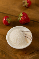 Strawberries and Coconut Flakes in a White Bowl on a Wooden Surface