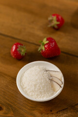 Strawberries and Coconut Flakes in a White Bowl on a Wooden Surface