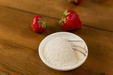 Strawberries and Coconut Flakes in a White Bowl on a Wooden Surface