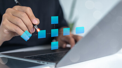 A businessman uses a digital pen and laptop to create a workflow diagram and a process management...