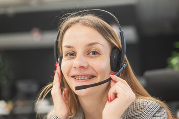 A woman with braces on her teeth talks on a headset. Helpdesk. 