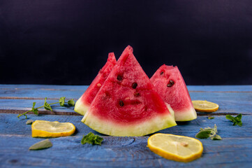 Fresh Watermelon Slices with Mint and Lemon on Blue Wooden Board Summer food