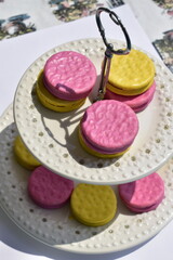 pink and yellow glazed biscuits on a porcelain two-tiered plate