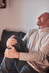 Man with painful knee and leg injury at home.