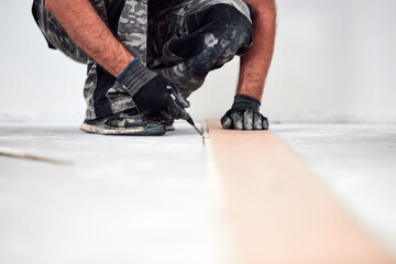 Professional handyman installing laminate flooring in a new apartment.
