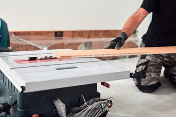 Professional handyman installing laminate flooring in a new apartment.
