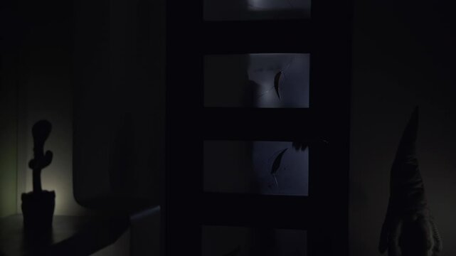 A man in a house picks the lock on a room door and enters inside