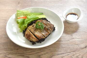 grilled slice chicken on black riceberry with cucumber carrot and lettuce on plate dipping Thai spicy tamarind sauce