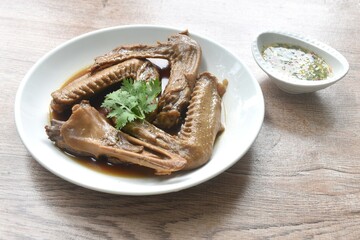 chop boiled duck wing and beak with tongue stew in brown soy soup on platedipping spicy sour chili sauce 