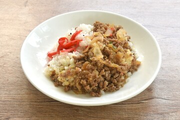 fried ground beef with onion or soboro donburi on rice black sesame topping pickled red ginger on plate