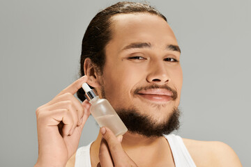 Charming young man with beard showcases skincare product in bright setting