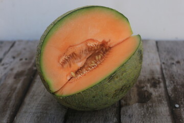 a melon that is cut open so that the orange flesh and many melon seeds are visible