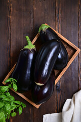 organic eggplant harvest in crate on log background, flat lay