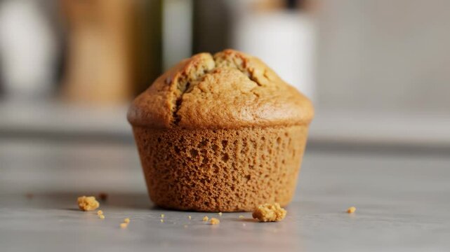 Delicious baked muffin on grey surface with crumbs, a bakery food concept.