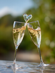 two golden champagne glasses clinking in a toast with a heart shape splashing forming