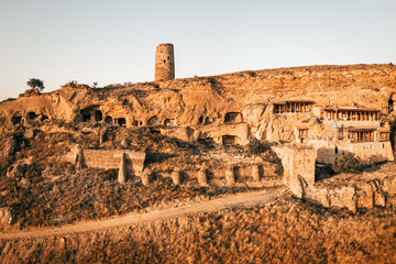 Aerial view of an ancient Orthodox monastery carved into remote cliffs amid vast hills, symbolizing...