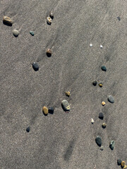 Pebbles scattered on dark sand