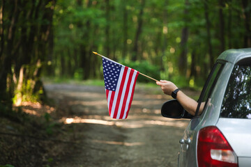 Man in the car holding a waving american USA flag.