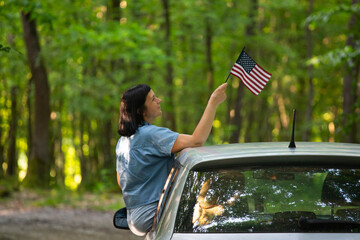 Woman in the car holding a waving american USA flag.