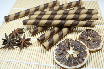 A pile of delicious striped wafer rolls arranged with aromatic star anise and dried lemon slices on...